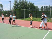 Des jeunes filles s'entraînant au tennis avec leur professeur.